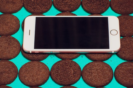 Modern mobile smartphone chocolate cookies stacked served milk the concept of a modern mobile operating systemの写真素材
