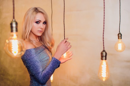 Blonde young woman in elegant blue summer dress. Girl posing on a beige background. Jewelry and hairstyle. Girl with handbag. Fashion photoの写真素材