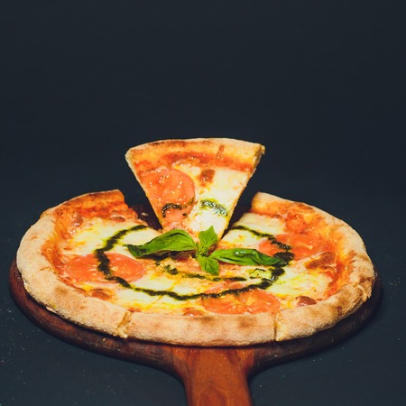Pizza pepperoni, mozzarella, oregano on a black backgroundの写真素材