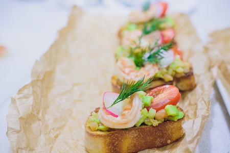 Bruschetta italian snack sandwiches with avocado cream and prawns decorated by parsley and chilli peppersの写真素材
