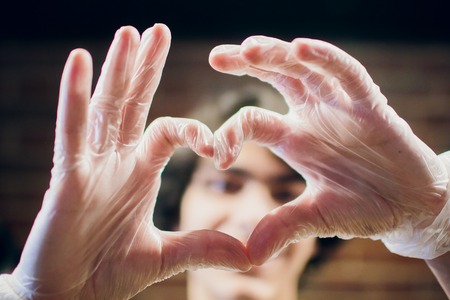 Chef hands in gloves making shape of heart, closeup loveの写真素材