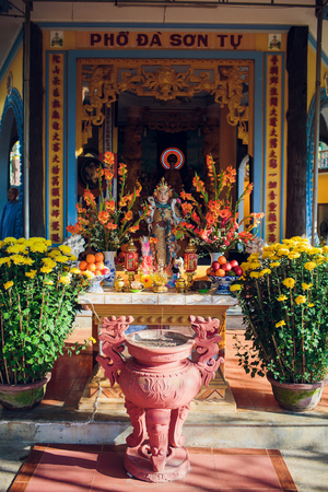 Altar at the feet of a standing Buddha in a Buddhist templeの写真素材