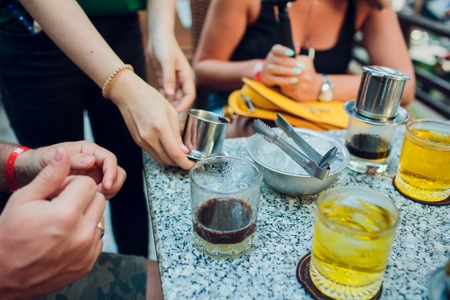 tourists drink Vietnamese coffee filter Cold Coffee cup with a bow of ice and coffee filter marker on the stone table. Vietnam Asiaの写真素材
