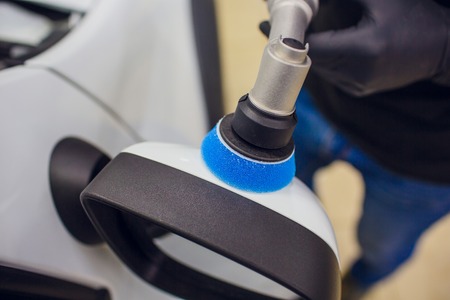 Car detailing - Worker with orbital polisher in auto repair shop. Car mirror polish. Selective...
