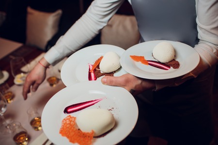 Waiters carrying plates with meat dish at a wedding foodの写真素材