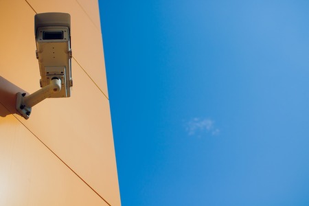 Modern CCTV camera on a wall. A blurred night cityscape background. Concept of surveillance and...