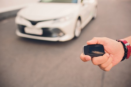 Male holding car keys with car on backgroundの写真素材