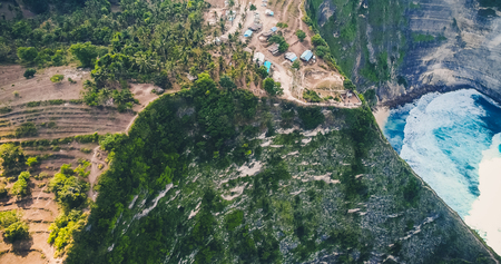 Drone view of a golf course next to the ocean with waves hitting the rocks on the seashoreの写真素材