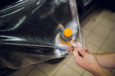 Worker hands installs car paint protection film wrapの写真素材