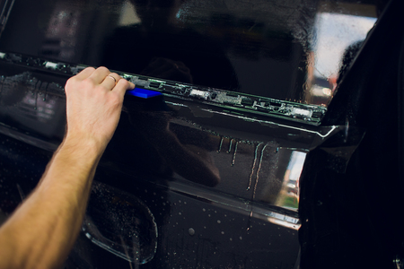 Worker hands installs car paint protection film wrapの写真素材