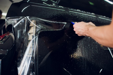 Worker hands installs car paint protection film wrapの写真素材