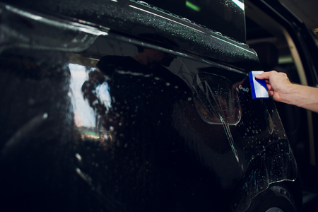 Worker hands installs car paint protection film wrapの写真素材