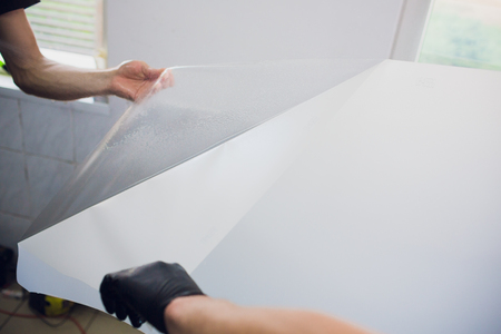 Worker hands installs car paint protection film wrapの写真素材