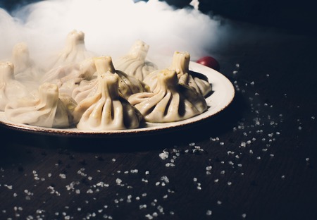 Georgian dumplings Khinkali with meat and tomato spicy sauce on cutting board