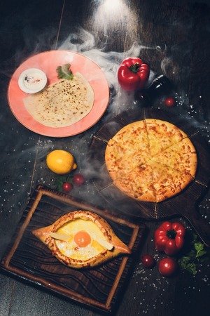 Khachapuri on a wooden texture with spices. Traditional Georgian cuisine.の写真素材