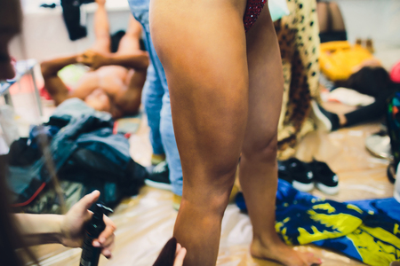 Bodybuilding competition backstage: contestant being oiled and fake tan applied to skinの写真素材