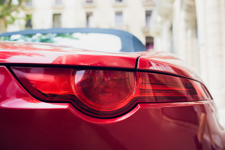 Detail of red metallized red rear car headlight in eye shape, with sun reflection in pupilの写真素材