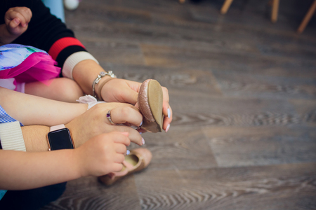 Young mom helping her little girl put on sandalsの写真素材