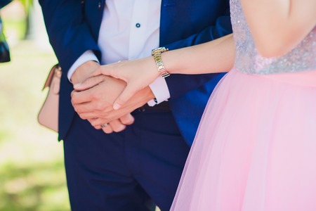 Beautiful young couple a man and a woman. Close-up hand of groom and bride with a wedding ring. Focus on the arm and the ring. bride in white dress. The picture is cropped without facesの写真素材