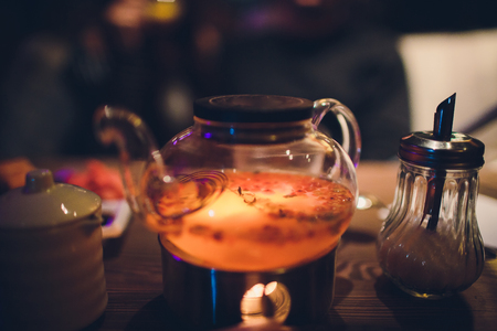 Teapot and glass cups with tea against wooden background. against the background of the restaurant in the eveningの写真素材