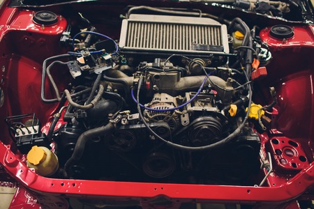 Car with open hood in auto repair shop