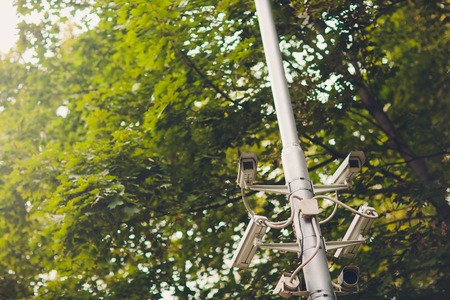 Cluster of security cameras on a lamppost in an old public Park on the background of spring foliage with copy spaceの写真素材