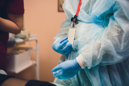 Close up of female doctor's hands putting on blue sterilized surgical gloves in the officeの写真素材