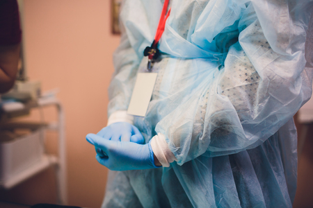Close up of female doctor's hands putting on blue sterilized surgical gloves in the officeの写真素材