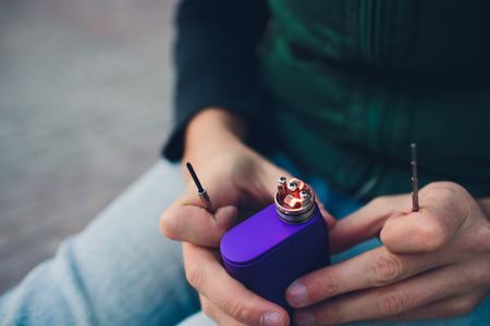 Maintenance of electronic mech mod vaping device.Modern vaporizer e-cig gadget to vape glycerin e-liquid.Vaper device repair service.Master replace wire for smoking.Ecig rapairing processの写真素材