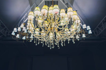 Big pendant layers lamps pattern on classic ceiling inside the hall in the nightの写真素材