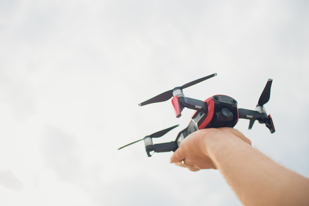 A man, a professional aerial photographer, launches a quadcopter or drone in the sky to take a video or photo of a terrain from a height. Man operating a drone with remote control.の写真素材