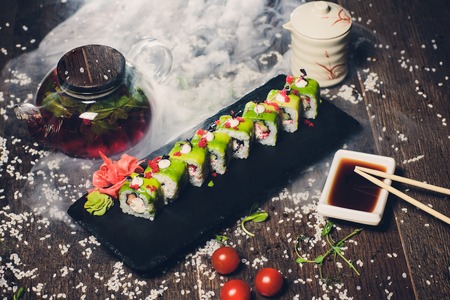 various sushi on white plate with chopsticks on wooden background.の写真素材