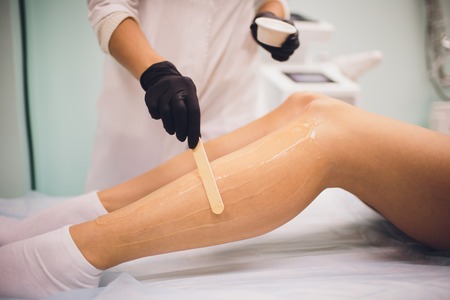 beauty, depilation, epilation, hair removal and people concept - beautiful woman with applicator applying depilatory wax to her leg.の写真素材