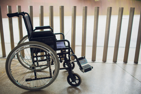 Empty modern wheelchair near brick wall indoors.の写真素材
