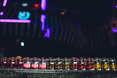 Variation of hard alcoholic shots served on bar counter. Blur bottles on background.の写真素材