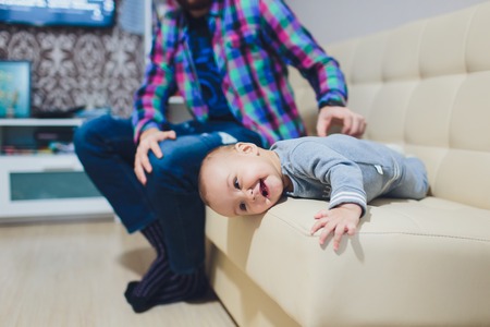 Happy young father playing with little daughter on the sofa.の写真素材