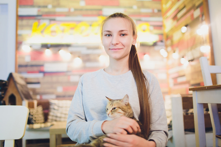 Beautiful young woman holding a red cat.の写真素材