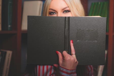 Reading and hiding behind a bookの写真素材