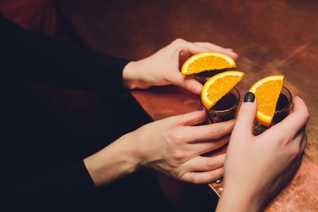 Three alcoholic drink in shot glasses with orange slices in the wood tableの写真素材