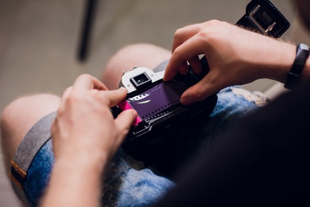 man installing a photo film cartridge in a film camera