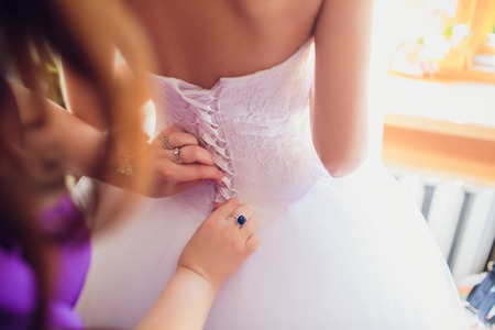 Bridesmaid is helping the bride to dressの写真素材
