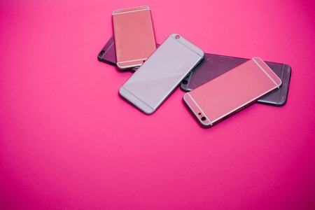 Broken mobile phone lies on a pink background.の写真素材