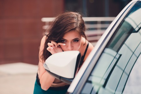 Smiling woman is reflected in mirror of car.の写真素材