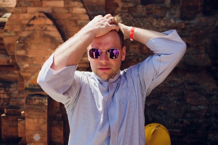 man in blue robe against background temple wall in sunglasses. CONCEPTION OF MODERN RELIGIONの写真素材