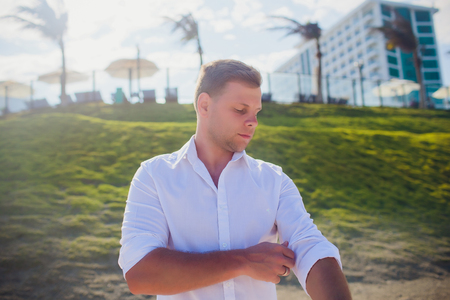 Handsome man wearing white clothes posing in sea sceneryの写真素材