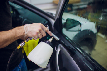 Handsome man cleaning car with hot steamの写真素材