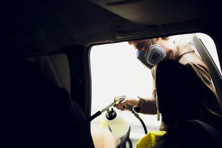 Handsome man cleaning car with hot steamの写真素材