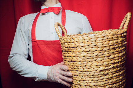 young handsome man holding basket in white and red uniformの写真素材