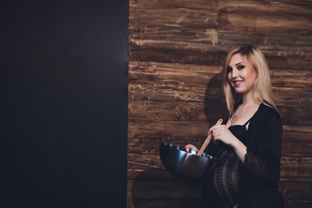 Attractive pregnant woman holding bowl kitchenの写真素材