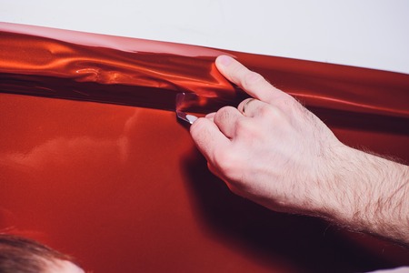 Car wrapping specialist putting vinyl foil or film on car. cutting protective film with torch....